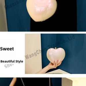 Detailed view of heart-shaped pearlescent evening clutch bag with golden metal frame