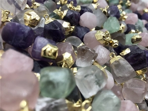 Detailed macro view of assorted natural raw gemstone pendants with gold plated clasps