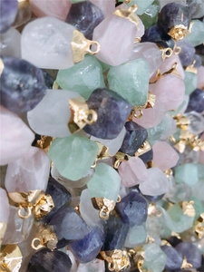 Close-up of assorted raw faceted natural stones with gold bails for jewelry DIY