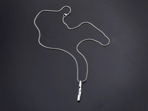 Detailed view of a silver twisted pillar pendant with metallic luster on a black background