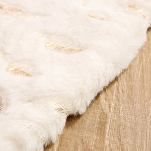 White faux fur Christmas tree skirt with elegant gold foil feather patterns on wood floor