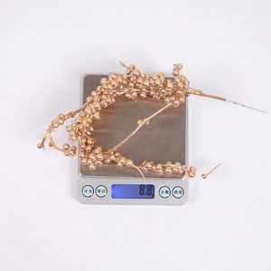 Nahaufnahme von leichten goldenen künstlichen Beeren auf einer Digitalwaage mit 8,8 g