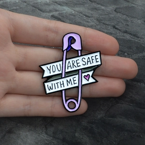 Lila Emaille Sicherheitsnadel Brosche mit You Are Safe With Me Herz Spruch in der Hand