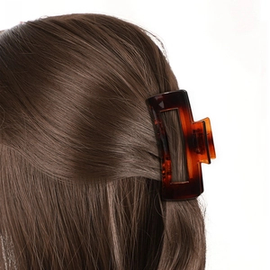 Detailed view of amber tortoise shell rectangle hair claw clip on dark brown hair