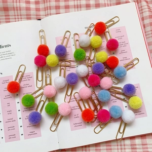 Colorful plush ball paper clips scattered on a book with red checkered background