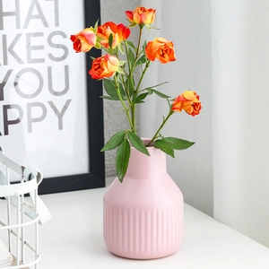 Pink fluted ceramic vase with orange roses and minimalist modern home decor background