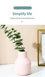 Detail of pink ceramic vase featuring vertical textures on a marble tabletop