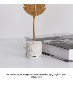 Macro shot of gold feather ornament with white terrazzo resin base for modern home decor