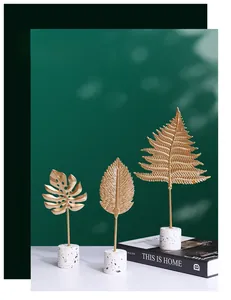 Detail of gold metal monstera leaves on a white terrazzo base for home decor