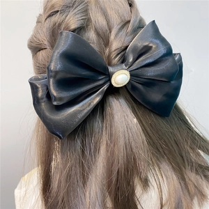 Detailed back view of a black satin double bow hair clip with a pearl center on a model