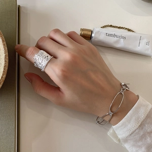 Detail of silver textured wide ring and matching link bracelet on model hand