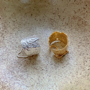 Macro shot of S925 sterling silver stamp and lava texture on gold and silver rings