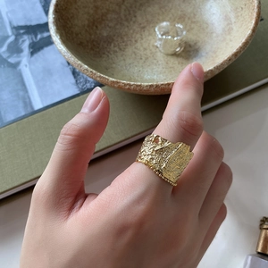 Macro detail of gold-plated wide ring with irregular textured lava finish on a model
