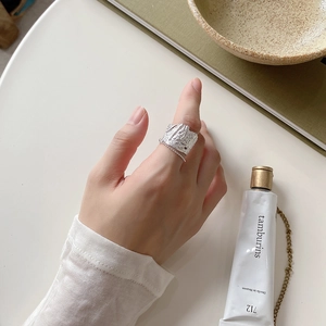 Detail of a wide sterling silver ring with irregular hammered texture and link chain