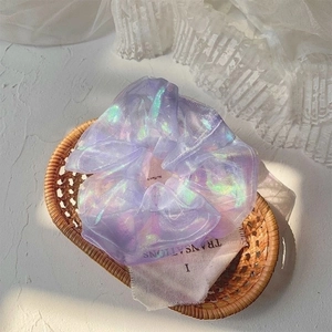 Close-up of lilac organza scrunchie with iridescent sheen inside a rustic woven basket