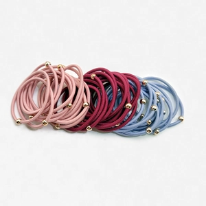Dettaglio di elastici per capelli rosa, bordeaux e blu con perline dorate lucide
