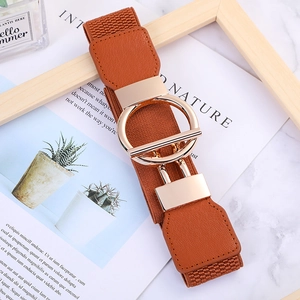Brown elastic waist belt with golden round buckle placed on magazine background