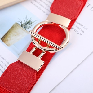 Close-up of a red elastic waist belt with a golden geometric buckle on a magazine