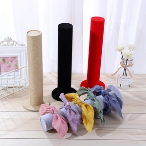 Macro detail of vertical jewelry stand featuring soft black velvet and linen fabric textures