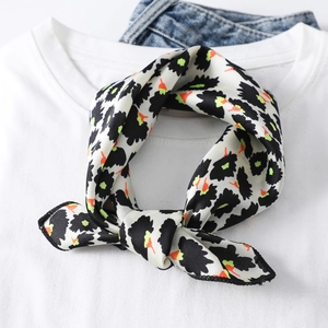Close-up of a knotted square silk scarf with black patterns and colorful dots on a tee