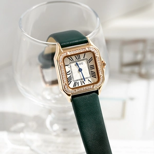 Macro view of vintage gold watch with green leather strap placed in a glass goblet