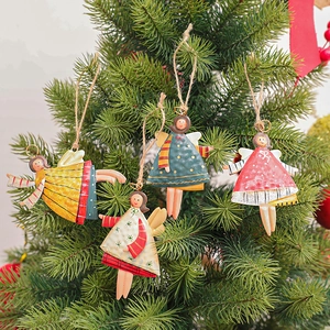 Set of four colorful painted metal angel Christmas tree ornaments hanging on green branches