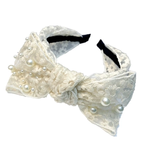 Elegant white lace headband with daisy patterns, pearls and a large bow tie knot
