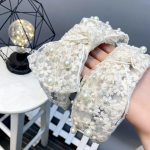 Close-up of white lace headband with floral embroidery and elegant faux pearls