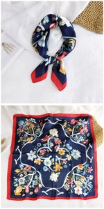 Detail of navy blue square silk scarf featuring colorful floral prints and red rolled edges