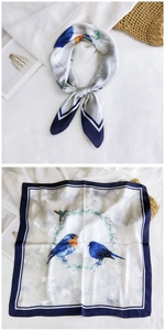 Detail of square silk scarf featuring blue bird and floral wreath print on white fabric
