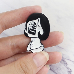 Close-up of surrealist black and white enamel brooch showing creative woman profile and stairs
