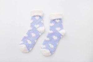 Detail of purple coral fleece socks with white heart patterns and plush turnover cuff