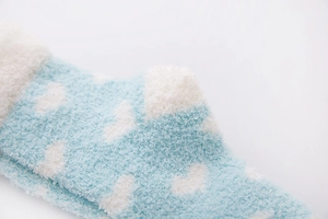 Close-up of soft coral fleece blue socks with white cloud pattern and fluffy texture