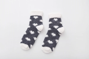 Detail of coral fleece socks in dark gray with white heart pattern and fluffy texture