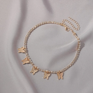 Close-up of golden butterfly choker with white rhinestones on grey fabric