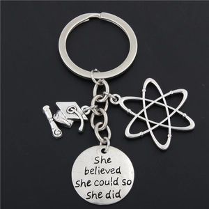 Metal teacher keychain with atom charm and graduation cap on black background