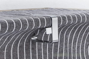 Close-up of polished stainless steel tablecloth clip securing a striped cloth to table edge