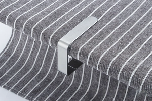 Macro shot of brushed stainless steel tablecloth clip in U-shape on a striped fabric