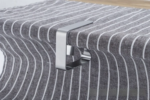 Close-up of brushed stainless steel tablecloth clip securing fabric on a table edge