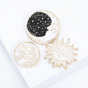 Macro shot of three celestial enamel pins featuring sun, moon, and wave designs