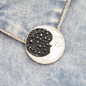 Detail of sun and moon enamel pin pinned on blue denim fabric showing celestial patterns