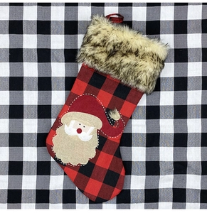 Détail d'une chaussette de Noël à carreaux rouges avec appliqué Père Noël en toile et fausse fourrure.