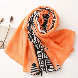 Detail of orange linen scarf with black and white geometric prints on minimalist background