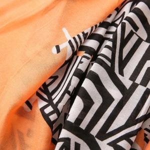 Detailed macro shot of lightweight orange fabric with modern black and white geometric patterns