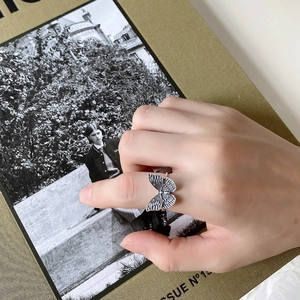 Detail of vintage silver butterfly ring on model's hand with aesthetic magazine backdrop