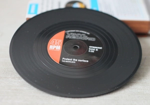 Macro shot of retro black vinyl record coaster with red label and 45 RPM print detail