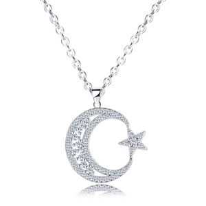 Macro shot of 18K gold star and moon pendant with shimmering cubic zirconia inlay