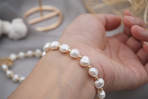 Detailed view of baroque freshwater pearl bracelet with 18K gold beads on woman wrist