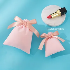 Pink velvet drawstring gift bags in two sizes with elegant satin bows on blue background