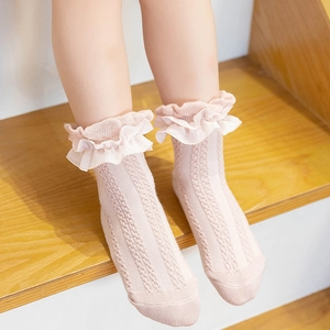 Pink knit baby socks with delicate lace trim for girls, shown on a wooden background